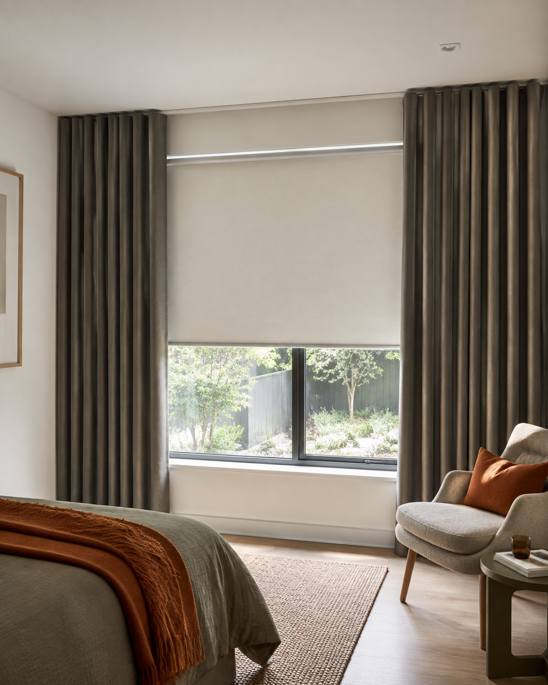 Roller blind mounted behind S-fold blockout curtains at a bedroom window